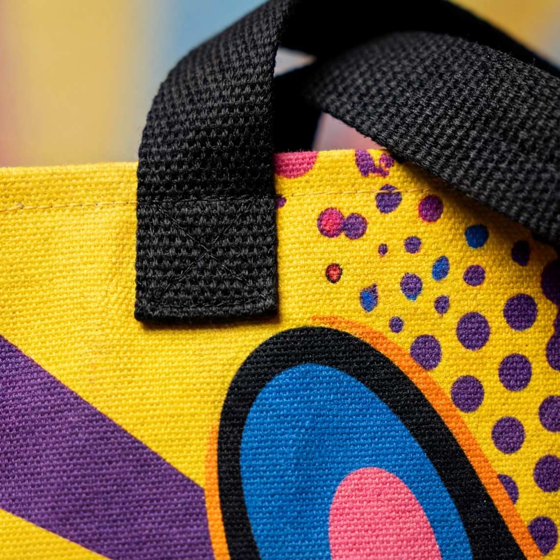 Close-up of a colorful bag with abstract patterns and black strap.
